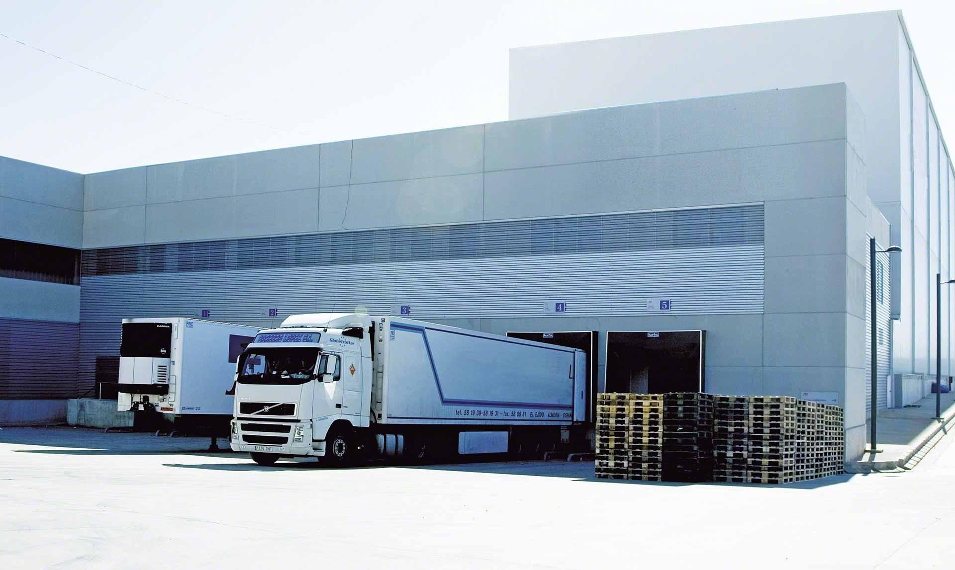Des camions déchargent leurs marchandises dans un entrepôt, étape intégrante des flux logistiques du cross-docking.