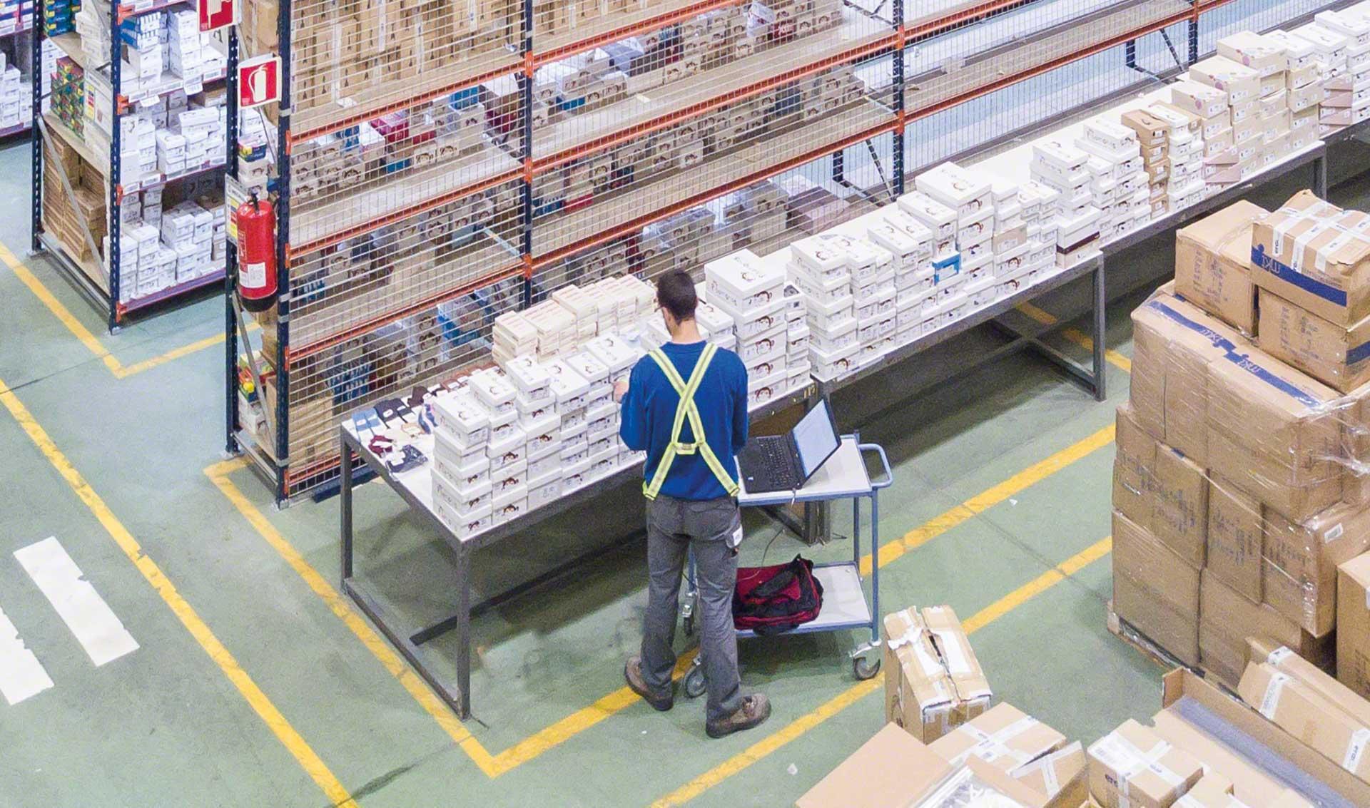 Un employé vérifie la conformité des produits d’un entrepôt à l’aide d’un ordinateur portable Un employé vérifie la conformité des produits d’un entrepôt à l’aide d’un ordinateur portable